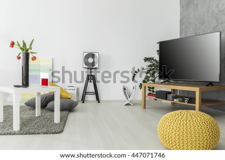 Modern living room with simple but trendy furniture and a tv set, arranged in grey and yellow