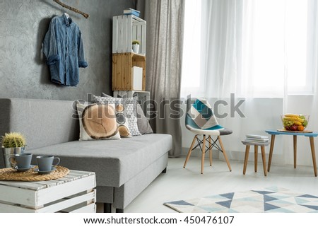 New style flat in grey with sofa, small table, chair, pattern carpet and beautiful home decorations