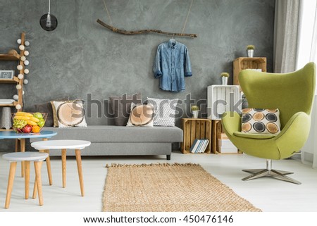 Cozy living room in grey with sofa, comfortable armchair and creative home decorations