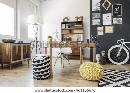 New style interior with ethnic commode, desk, chair, pouffe, bike and blackboard wall