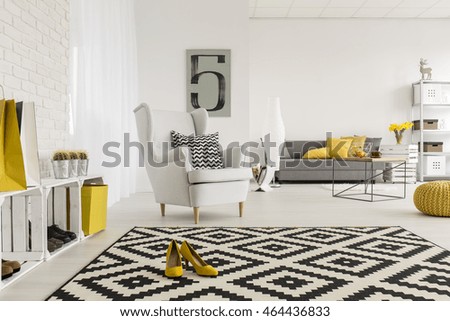 Very spacious living room in white, with yellow decorations and high-heeled shoes in the middle of a modern carpet