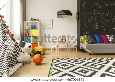 Shot of a kids room with a grey sofa, large blackboard and a place for learn