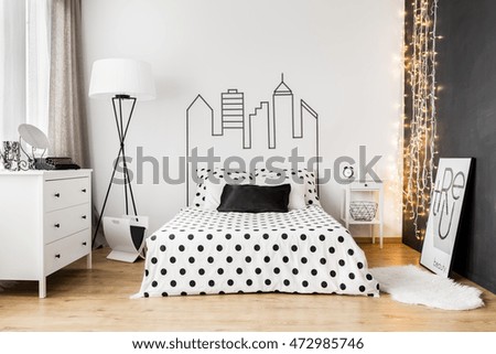 Bright bedroom interior with wide bed, commode and one black wall