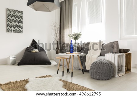 Light livng room with bean bag, comfortable sofa, DIY table, window and stylish decorative details