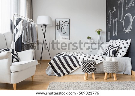 Cozy bedroom with blackboard wall, clothes rack and armchair