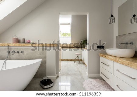 Bright, spacious bathroom with big, oval bathtub, white amenities and modern weight on the floor