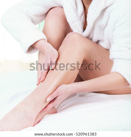 Woman rubbing lotion on her legs after depilation
