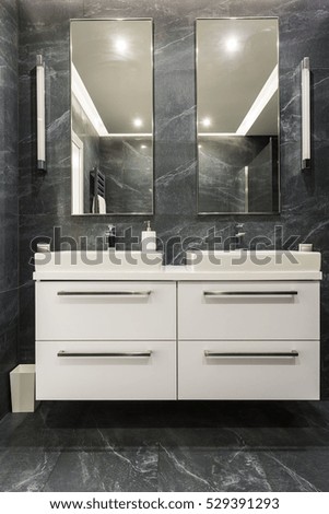 Dark granite bathroom with white cabinet and two sinks with mirrors