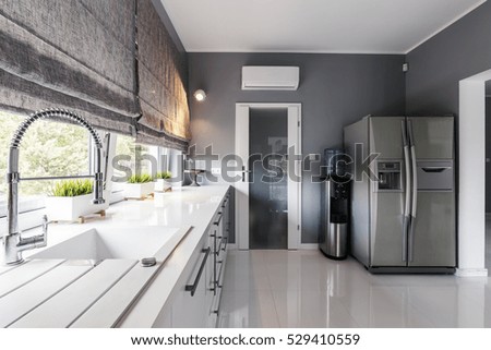 Modern kitchen with big windows, elegant kitchen units and silver fridge