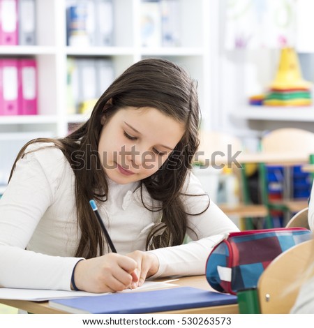 Young girl writing an essay during lesson in primary school