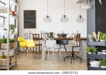 Room with communal table, chairs, industrial regale and cart