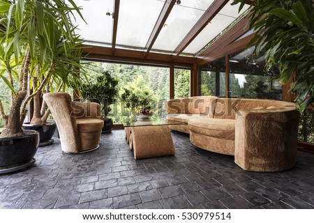Comfortable plush lounge set in a conservatory with dark stone floor