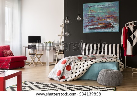 Cozy modern studio with red and blue accessories and bed