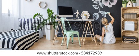 Modern creative studio interior and a woman painting on a chalkboard wall