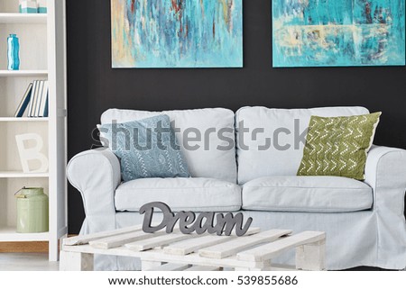 Grey sofa in modern living room with paintings on the wall