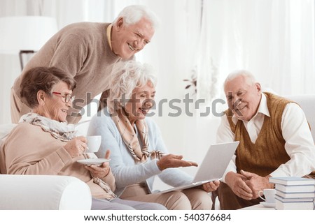 Elderly people using computer, sitting in light room