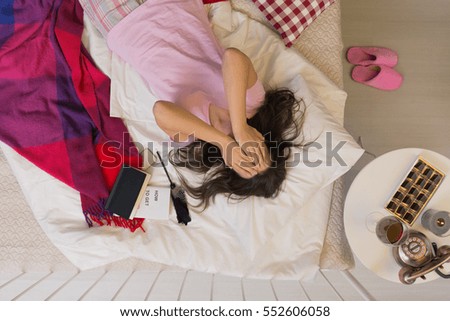 Depressed woman lying in bed, covering her face