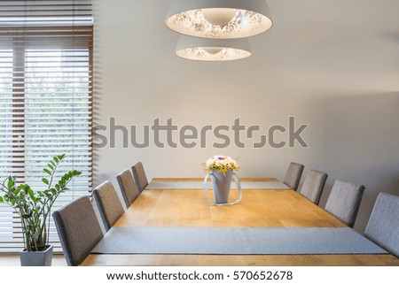 Home interior with wooden dining table, chairs and pendant lamp