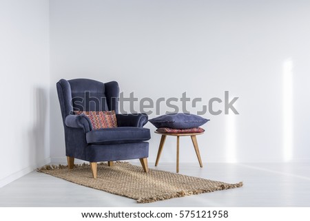 White interior with navy blue armchair, rug and side table