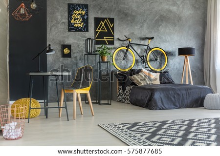 Grey student room with bed, desk, bike and copper lamps