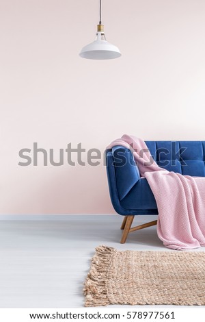 Light pink living room with blue sofa, rug and lamp