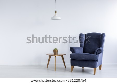 Bright interior with blue armchair, ceiling lamp and side table