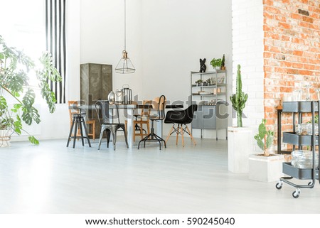 Bright loft interior with communal table, chairs and brick wall