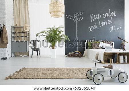 Spacious travel-themed bedroom with chalkboard wall, plant, books and toy car