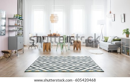 Functional apartment with dining table, sofa and pattern rug