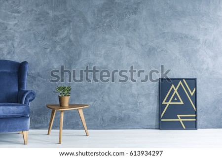 Blue armchair and little wooden table in blue and white room