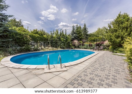 Oval swimming pool in a garden area, surrounded by plants