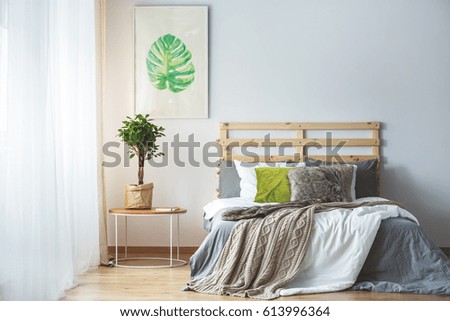 Pastel bedroom interior with green accessories and monstera poster