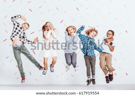 Happy group of kids jumping in a room with decorative tape on the wall