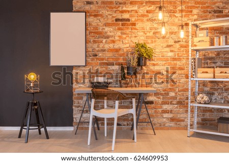 Loft apartment with brick wall, desk, chair, chalkboard, lamp, plants
