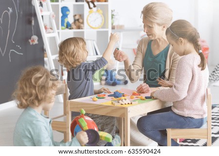 Group of kids on art classes with teacher in kindergarten