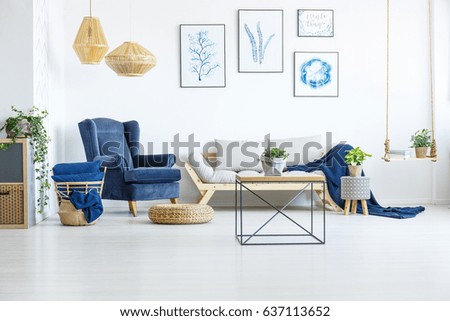 White living room wih navy blue armchair, sofa and posters