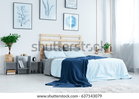 Simple bedroom with double bed, blue bedding, posters and window