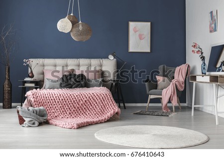 Dark grey comfy armchair with cushion and pink blanket in the corner of the room
