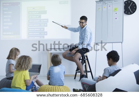 Teacher shows students how to program on an interactive whiteboard. Modern teaching concept