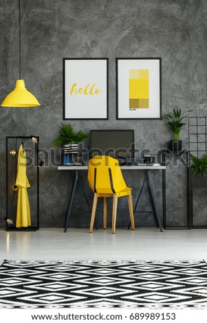 Room with metal desk, yellow accents, textured wall and mock-up posters