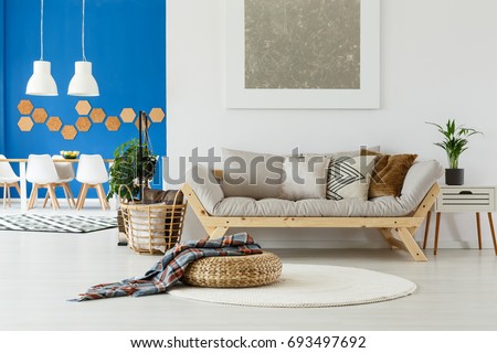 Natural design in contemporary interior of open plan apartment with dining space, beige sofa, plants and blue wall