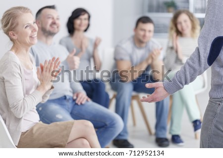 Man standing in front of applauding support group after making progress