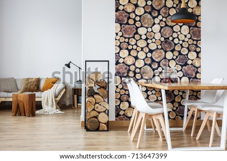 Open dining room interior with firewood, communal table and wooden log wall decoration for warm cozy atmosphere