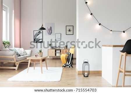 Lighting in bright living room with striped blanket on yellow chair next to table on white carpet