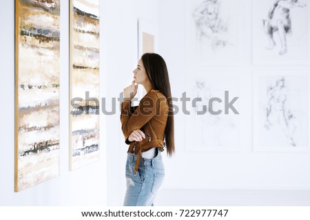 Young woman observing painting while visiting art gallery with famous artist collection