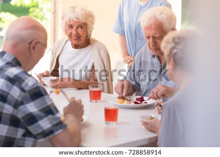 Group of pensioners eating lunch together at the rest home
