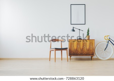 Trendy spacious room with antique wooden furniture, white wall, cupboard, chair and vintage bike