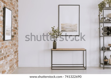 Simple painting above wooden console table with twigs in a glass vase in modern living room interior