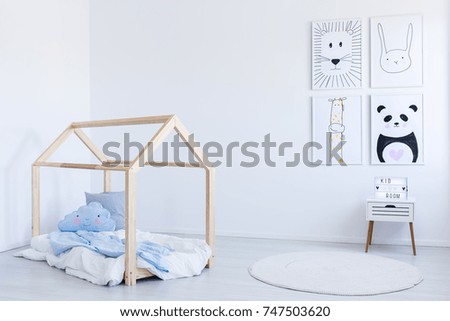 Blue bedsheets and pillows on wooden do it yourself bed in white boy\'s room with contrast color drawings