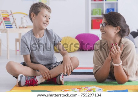 Happy little child during during therapy with school counselor, learning and having fun together sitting on the floor in a colorful playroom